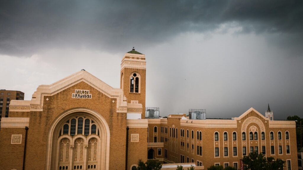 A dramatic view of the First Baptist Church building with ominous storm clouds overhead.